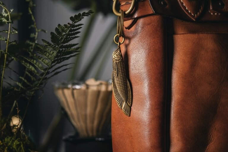 Close-up of a leather bag adorned with a golden fish-shaped keychain. Stylish accessory.
