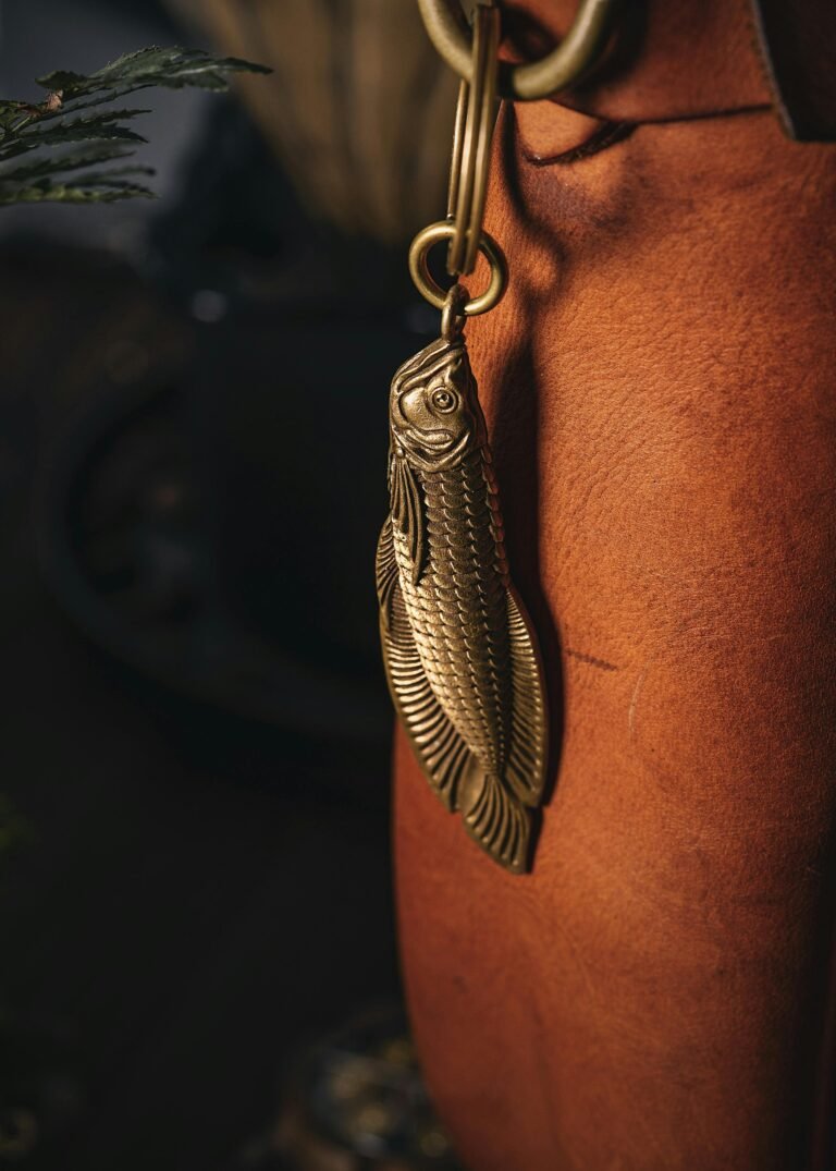 Elegant handmade brass fish keychain attached to a leather bag, perfect for gifts.