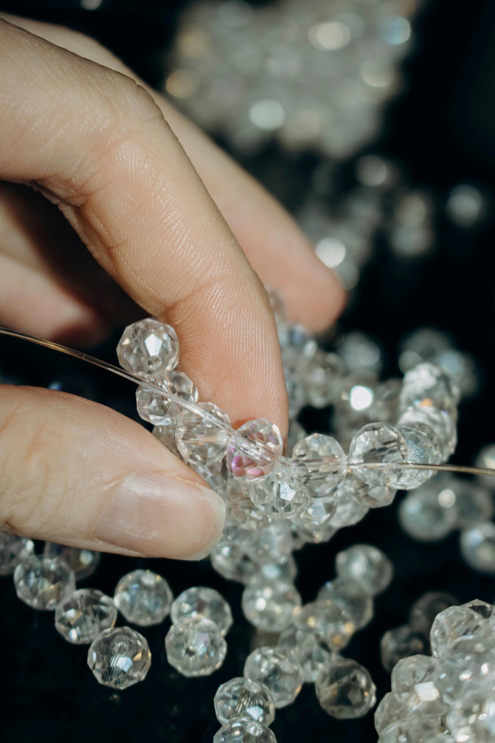 A close-up view of a hand skillfully holding crystal beads, showcasing jewelry crafting.
