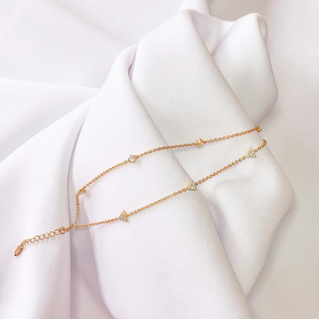 A delicate gold necklace beautifully displayed on soft white fabric, showcasing luxury and elegance.